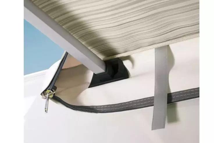 Weißer Bezug mit offenem schwarzem Reißverschluss, silbernem Reißverschlussanhänger, grauem Stoffstreifen, schwarzem Kunststoffhalter, hellbeigem gestreiftem Polster und weißem Balken