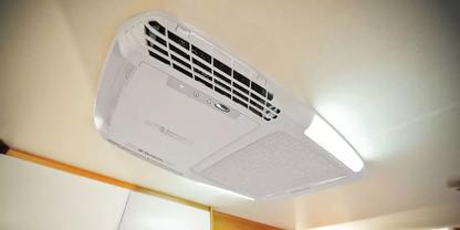 Wei&szlig;es rechteckiges Ger&auml;t an der Decke mit L&uuml;ftungsgittern und Licht, Holzleiste am Rand sichtbar