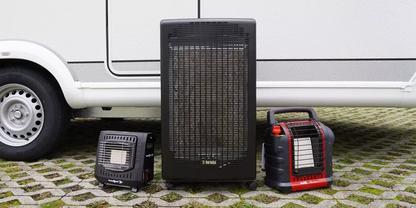 Drei tragbare Heizger&auml;te (ein hohes schwarzes in der Mitte, zwei kleinere links und rechts) vor einem wei&szlig;en Fahrzeug auf gepflastertem Boden