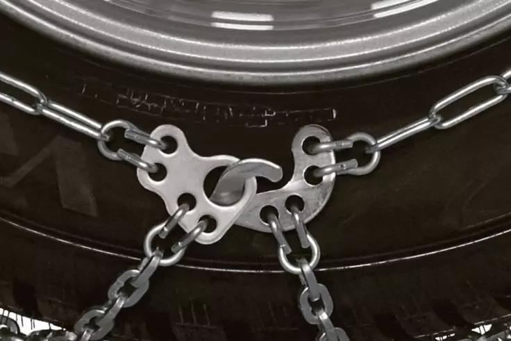 Nahaufnahme eines Reifens mit metallischen Schneeketten und Verbindungsplatte