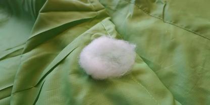 Wei&szlig;es Watteb&auml;llchen auf gr&uuml;nem, gefaltetem Stoff