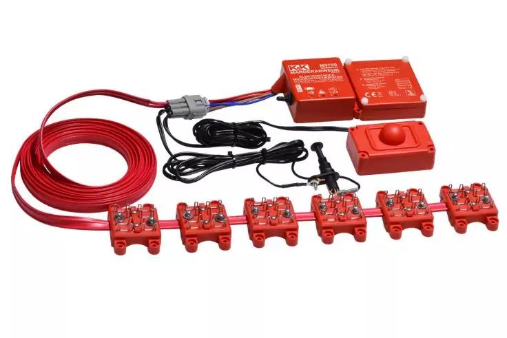 Mehrere rote elektronische Module in einer Reihe, ein rotes Kabel, zwei rote Steuerkästen und ein roter Taster, verbunden durch schwarze Kabel auf weißem Hintergrund