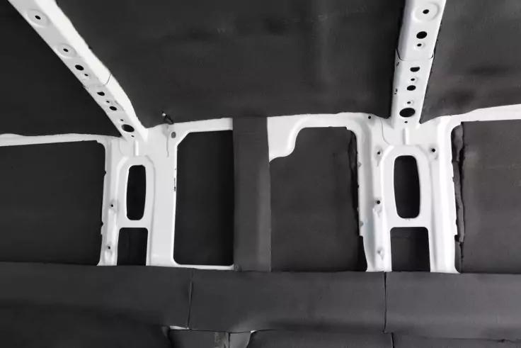 Decke mit weißen Metallträgern und dunklen Polster- oder Isolierplatten