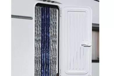 Geöffnete weiße Wohnwagentür; dahinter dunkelblau-grau gemusterter Vorhang