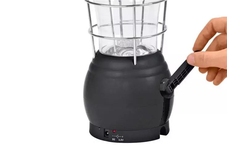 Schwarzer, runder Sockel mit Metallgitteraufsatz und klarem Glasgef&auml;&szlig;; Hand stellt einen seitlichen schwarzen Drehhebel ein; vorn Ein-/Aus-Schalter und Anschlussbuchse sichtbar; wei&szlig;er Hintergrund