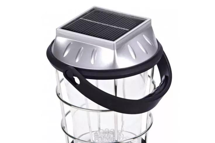 Metallene Oberseite mit Solarpanel, schwarzer Tragegriff, durchsichtiger zylindrischer Kunststoffk&ouml;rper mit kleinen wei&szlig;en Kugeln innen und metallischen Ringen au&szlig;en