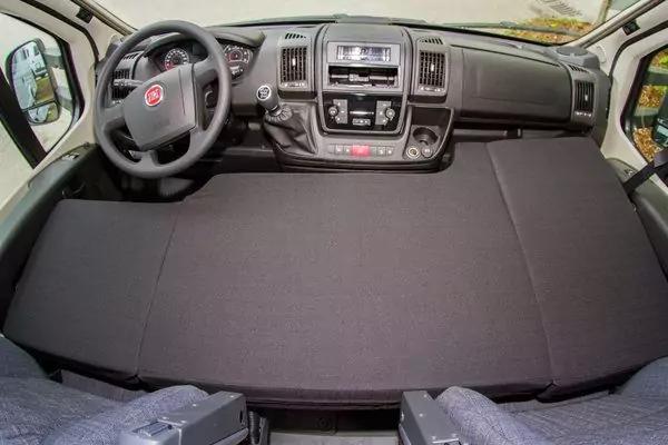 Fahrzeug-Innenraum mit Lenkrad und Fiat-Logo, Armaturenbrett und Radio; gro&szlig;e dunkelgraue Stofffl&auml;che &uuml;ber dem Sitzbereich; zwei Vordersitze und Au&szlig;enspiegel sichtbar