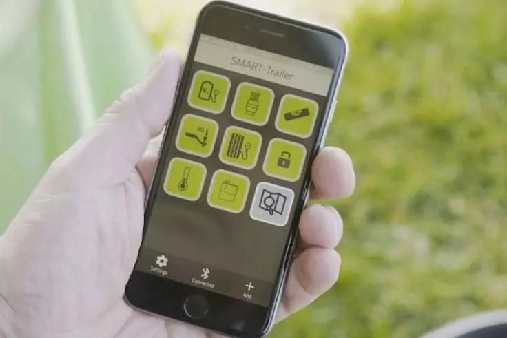 Hand hält ein Smartphone, auf dem ein App-Bildschirm mit neun grünen quadratischen Symbolen zu sehen ist; unscharfer grüner Hintergrund