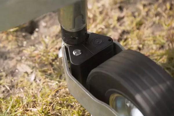 Nahaufnahme eines schwarzen Gummirads in einer Metallhalterung auf Gras