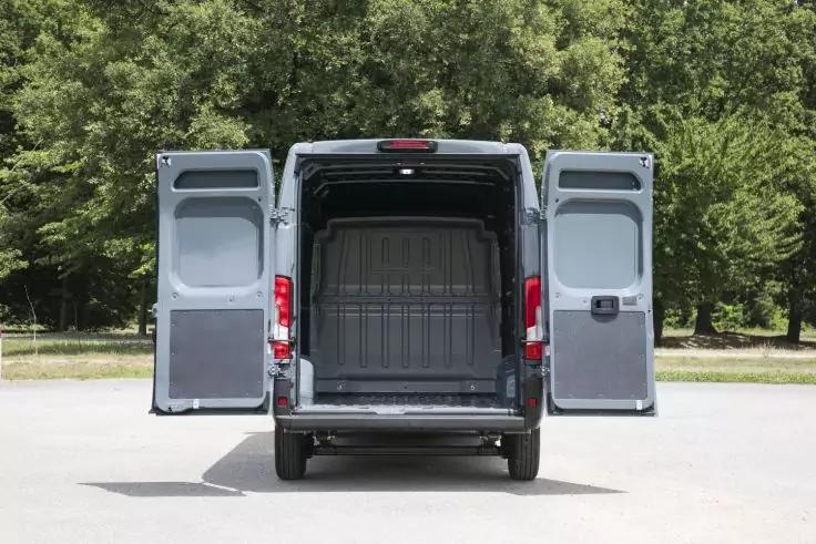 Leerer Transporter mit ge&ouml;ffneten Heckt&uuml;ren, Blick in den Laderaum, geparkt vor B&auml;umen