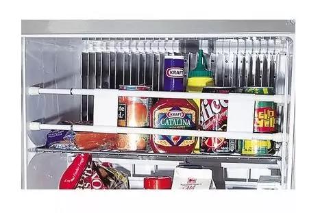 K&uuml;hlschrankinnenraum mit Metallgitterregal. Auf dem Regal mehrere Gl&auml;ser, Dosen und Kunststoffflaschen, darunter ein Glas mit 'KRAFT'-Etikett, eine Dose mit 'CATALINA'-Aufdruck, eine gr&uuml;n-gelbe Spritzflasche, bunte Dosen und verpackte Produkte