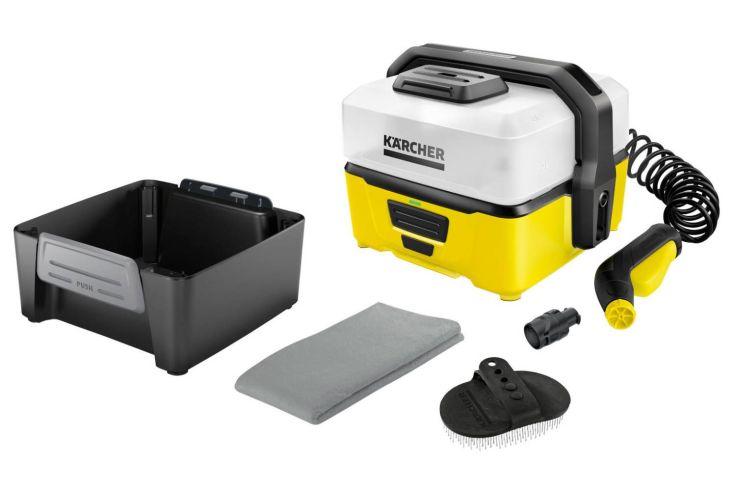 Gelb-weißes tragbares Reinigungsgerät mit schwarzem Griff, aufgewickeltem schwarzen Schlauch und gelb-schwarzer Sprühpistole; daneben schwarzer Einsatzbehälter, graues Tuch und zwei Bürstenaufsätze auf weißem Hintergrund