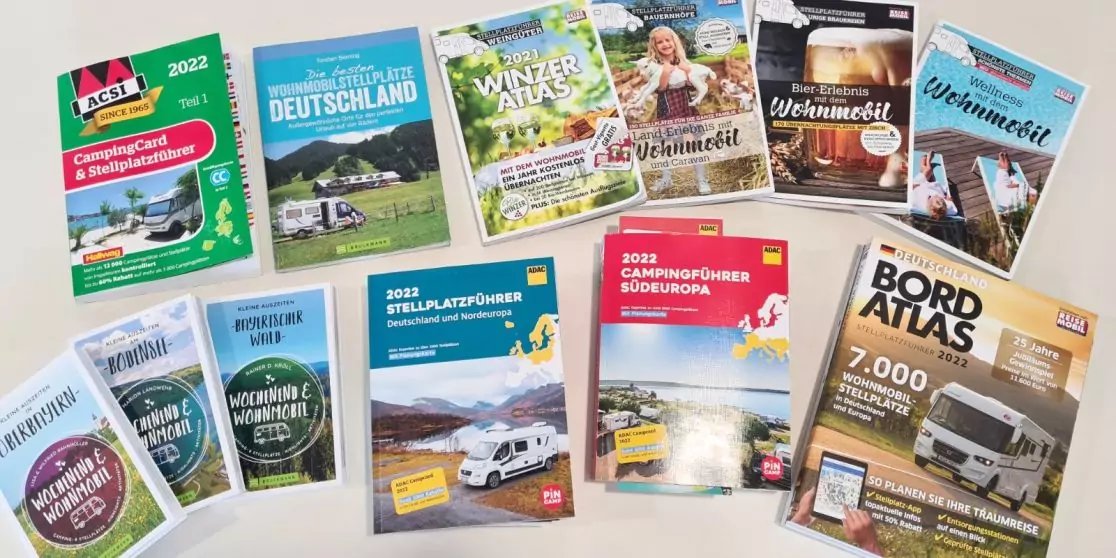 Mehrere B&uuml;cher und Hefte mit bunten Titelseiten, Fotos und Schriftz&uuml;gen liegen nebeneinander auf hellem Untergrund