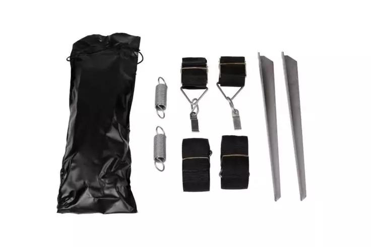 Schwarze Tasche, zwei Federkarabiner, zwei gepolsterte Gurte mit Metallhaken, zwei kurze Stoffriemen und zwei lange flache Metallteile auf wei&szlig;em Hintergrund