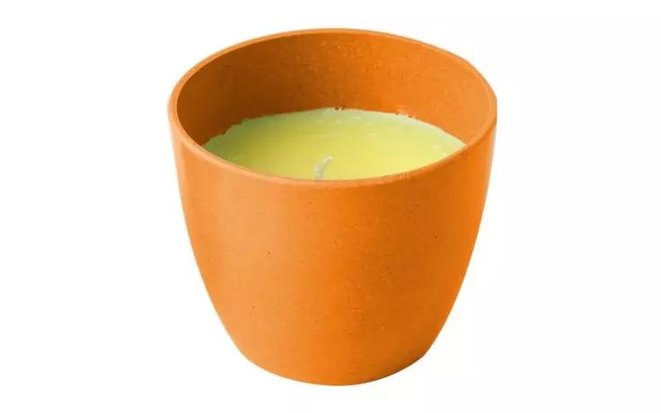 Orangefarbener runder Beh&auml;lter mit gr&uuml;ner Kerzenwachsfl&auml;che und einem Docht auf wei&szlig;em Hintergrund