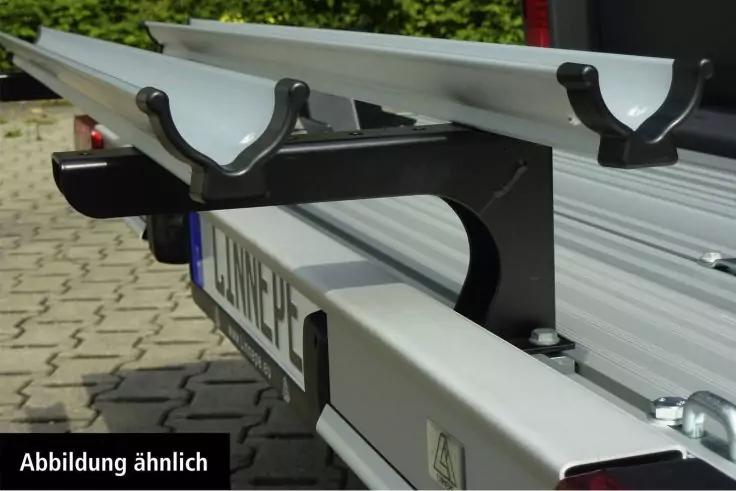 Nahaufnahme von zwei silbernen U-f&ouml;rmigen Schienen auf einer schwarzen Metallhalterung &uuml;ber einer hellen Aluminiumschiene, Pflasterboden und Gr&uuml;nfl&auml;che im Hintergrund; unten links Schriftzug 'Abbildung &auml;hnlich'