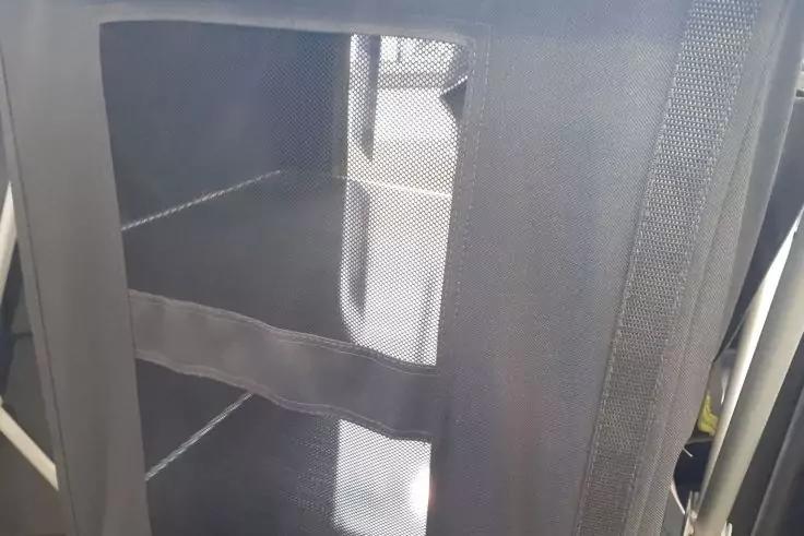 Schwarzes Netzstoff-Panel mit mittigem horizontalem Stoffband, vertikaler Naht rechts, heller rechteckiger Reflex in der Mitte und sichtbaren Rahmenkanten links und rechts