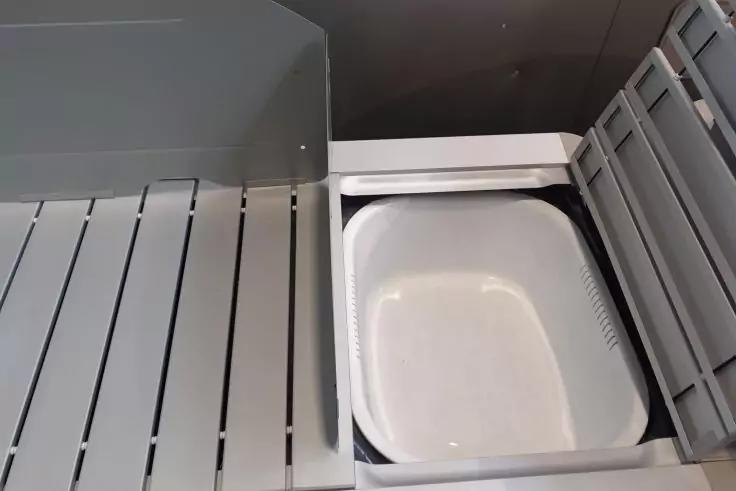 Graue Gitter mit L&auml;ngsschlitzen links und rechts, in der Mitte eine wei&szlig;e, rechteckige flache Plastikschale