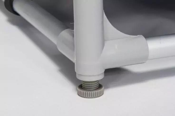 Nahaufnahme eines wei&szlig;en/hellgrauen Rohrgestells mit T‑Verbindung und verstellbarem Stellfu&szlig; mit sichtbarem Gewinde auf hellem Untergrund