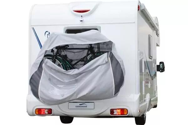 Heck eines wei&szlig;en Wohnmobils mit offener grauer Stofftasche an der R&uuml;ckwand, in der zwei Fahrr&auml;der mit sichtbaren Rahmen und R&auml;dern stecken; R&uuml;ckleuchten und Kennzeichenhalter sichtbar
