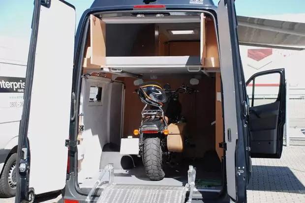 Ge&ouml;ffnete Heckt&uuml;ren eines Lieferwagens, ausgeklappte Metallauffahrrampe und ein Elektromobil im Laderaum; Innenverkleidung und ge&ouml;ffnete Seitent&uuml;r sichtbar