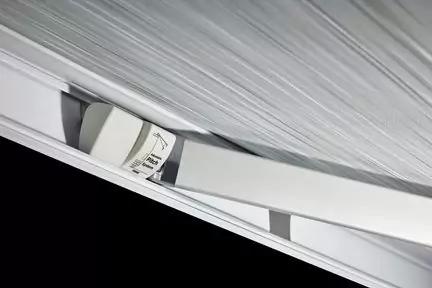 Nahaufnahme einer wei&szlig;en Metall-/Kunststoffschiene mit Halterung und kleinem Aufkleber vor einer grauen, strukturierten Fl&auml;che