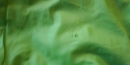 Gr&uuml;ner Stoff mit Falten und zwei kleinen Wassertr&ouml;pfchen