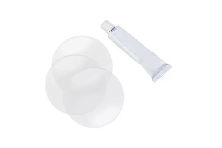 Zwei runde, d&uuml;nne, halbtransparente wei&szlig;e Scheiben neben einer kleinen wei&szlig;en Tube mit Schraubverschluss