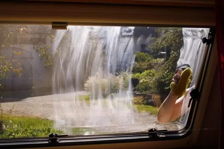 Fensterblick auf fallendes Wasser vor einem Haus; rechts eine Person h&auml;lt ein gelbes Telefon ans Ohr