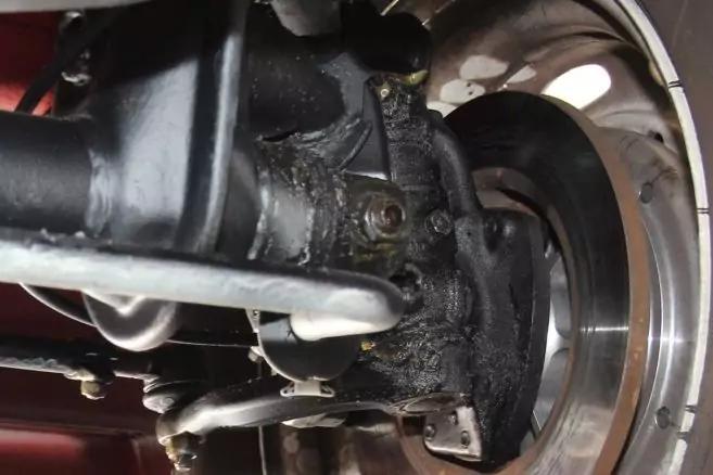 Nahaufnahme einer Radnabe und Bremsscheibe eines Fahrzeugs, Achs- und Lenkgest&auml;nge sichtbar, dunkle R&uuml;ckst&auml;nde auf der Nabe