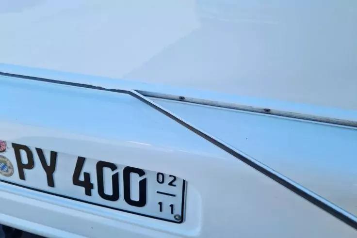 Nahaufnahme der R&uuml;ckseite eines wei&szlig;en Autos mit sichtbarem Kennzeichen PY 400 und Chromleisten am Kofferraum