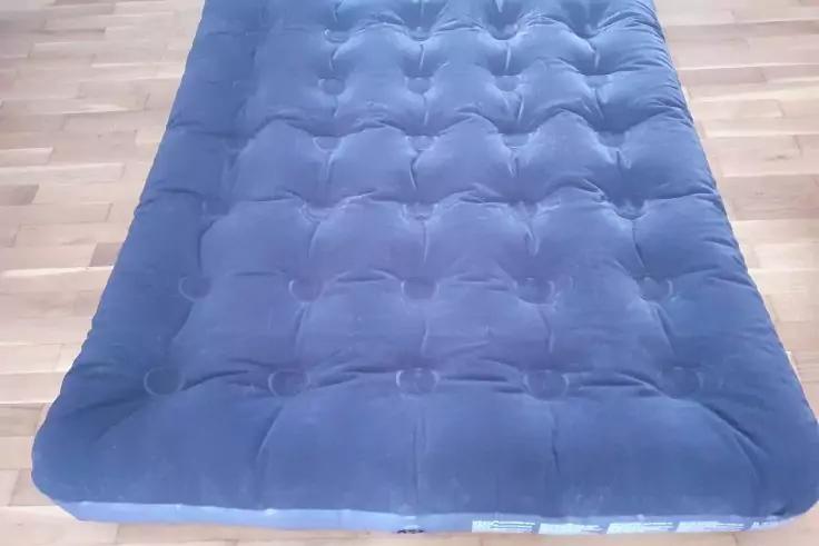Gepolsterte, blaue rechteckige Matratze mit Steppn&auml;hten auf hellem Holzboden