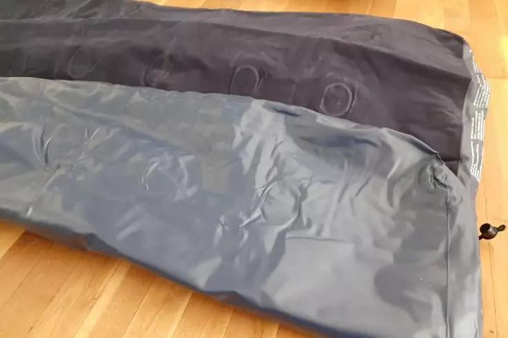 Zwei graue, l&auml;ngliche Stoffbeutel mit Kordelzug liegend auf einem Holzboden