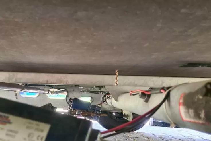 Metallrahmen, rote und schwarze Kabel, zylindrisches Rohr, elektronische Bauteile, Betonboden