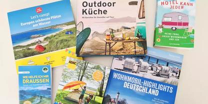 Sieben Brosch&uuml;ren auf hellem Untergrund, sichtbare Titel: 'Let's camp!', 'Outdoor K&uuml;che', 'Hotel kann jeder', 'Wohnmobil-Highlights Deutschland', Bilder von Zelt, Wohnmobil und Strand