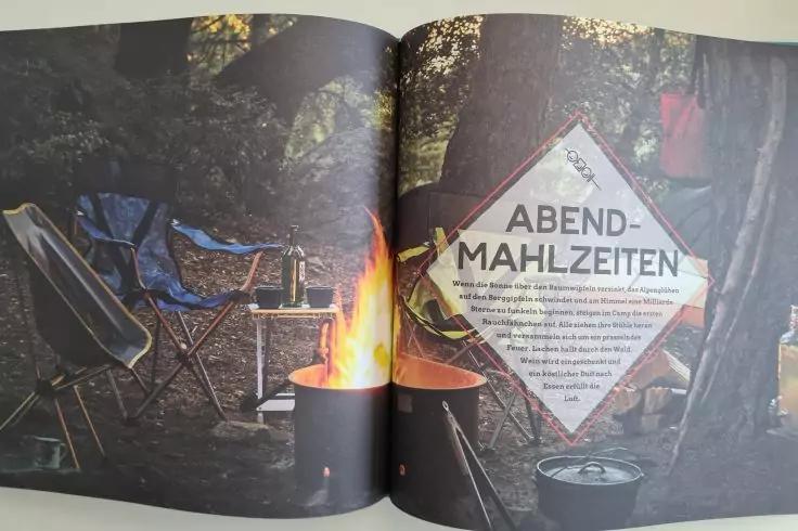 Aufgeschlagene Magazinseite mit Campingmotiv: brennende Feuerschale in der Bildmitte, zwei Campingst&uuml;hle links, Zelt und Campingausr&uuml;stung im Hintergrund, rechte Seite mit rhombusf&ouml;rmigem Feld und dem Wort &bdquo;ABEND-MAHLZEITEN&ldquo; sowie kleingedrucktem Tex
