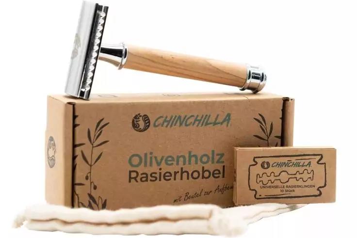 Rasierhobel mit hellem Holzgriff auf einer Kartonbox mit Aufdruck 'Olivenholz Rasierhobel', daneben eine kleine Schachtel mit Bild einer Rasierklinge und eine gedrehte weiße Schnur
