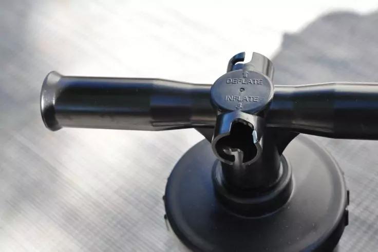 Schwarzer Kunststoff-Saugfuß mit kreuzförmigem Griffaufsatz auf heller, leicht strukturierter Fläche