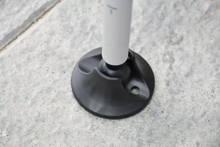 Unterer Teil eines wei&szlig;en Rohres mit schwarzem Gummifu&szlig; auf hellem Betonboden