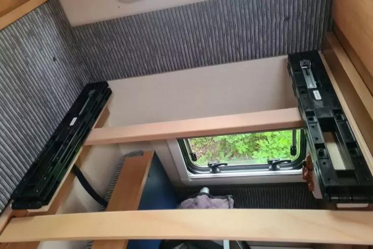 Innenraum mit Holzlatten, Metallf&uuml;hrungen, gerippter Wandverkleidung, Seitenfenster mit Verschluss und gr&uuml;nem Au&szlig;enblick