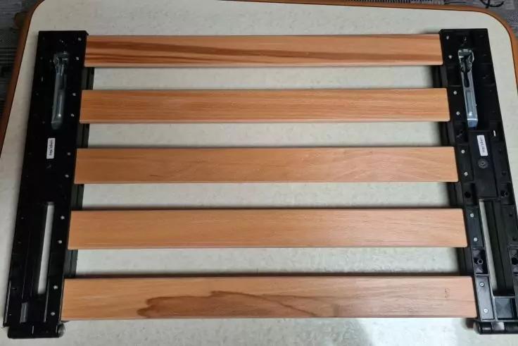 F&uuml;nf horizontale Holzlatten zwischen zwei schwarzen Metallprofilen auf hellem Untergrund