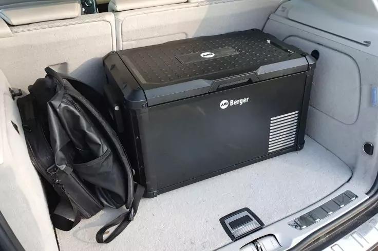 Schwarze tragbare K&uuml;hlbox mit Beyer-Logo auf hellem Kofferraumteppich, links eine zusammengefaltete schwarze Tasche
