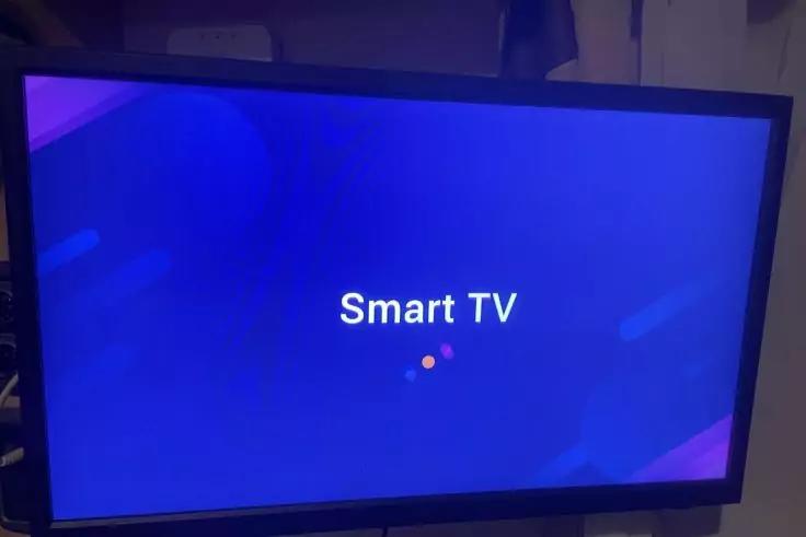 Fernseherbildschirm mit blauem Hintergrund, wei&szlig;em Text 'Smart TV' mittig und zwei kleinen farbigen Punkten darunter