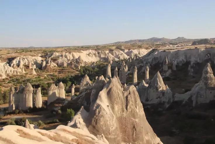 Tal mit zahlreichen hohen, spitz zulaufenden beigen und grauen Felsformationen, vereinzelte B&uuml;sche und blauer Himmel