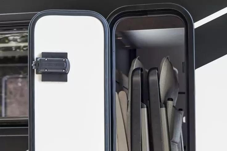 Offene wei&szlig;e T&uuml;r eines Stauraums mit schwarzem Rahmen, innen mehrere gefaltete graue St&uuml;hle