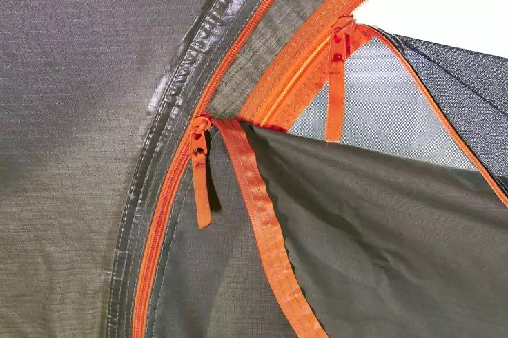 Nahaufnahme eines grauen Zelts mit orangefarbenem Rei&szlig;verschluss und Netzstoff