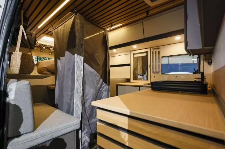 Innenraum mit Holzlamellendecke, Regal mit Tasche, Vorhang, gepolsterter Sitz, Schubladen und Fenster