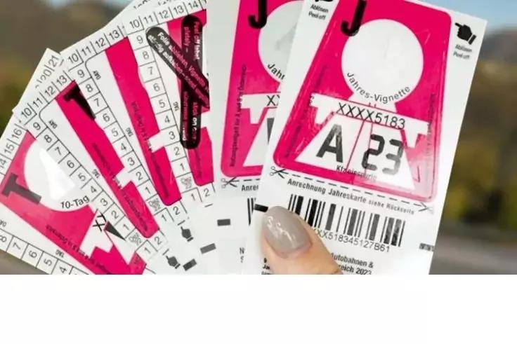 Hand mit hell lackierten Fingern&auml;geln h&auml;lt gef&auml;chert mehrere rosafarbene Aufkleber mit Barcodes, aufgedruckten Buchstaben und Zahlen und runden Ausschnitten; unscharfer Hintergrund