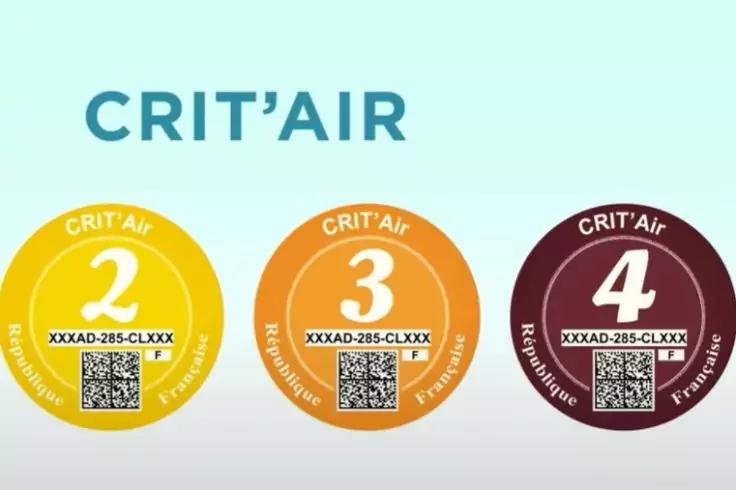 Oben der Schriftzug "CRIT'AIR", darunter drei runde Plaketten: gelb (Zahl 2), orange (Zahl 3) und dunkelrot (Zahl 4) mit QR-Codes und alphanumerischer Kennung