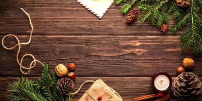 Holzbrett mit Tannenzweigen, Kiefernzapfen, Waln&uuml;ssen und Haseln&uuml;ssen, eingepacktes Geschenk mit Schnur, Kerze in Halter, Zimtstangen und Kordel